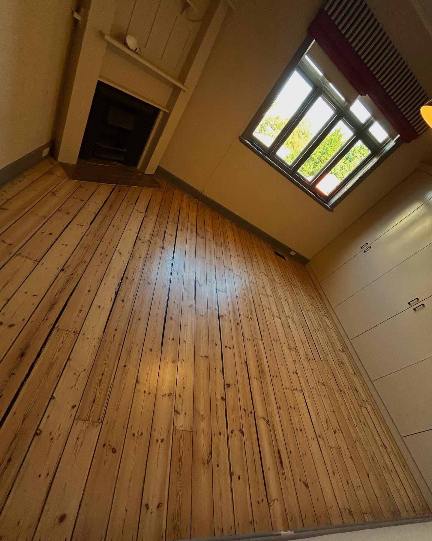 1-home-about-section2 Light timber floorboards in an empty room with a fireplace