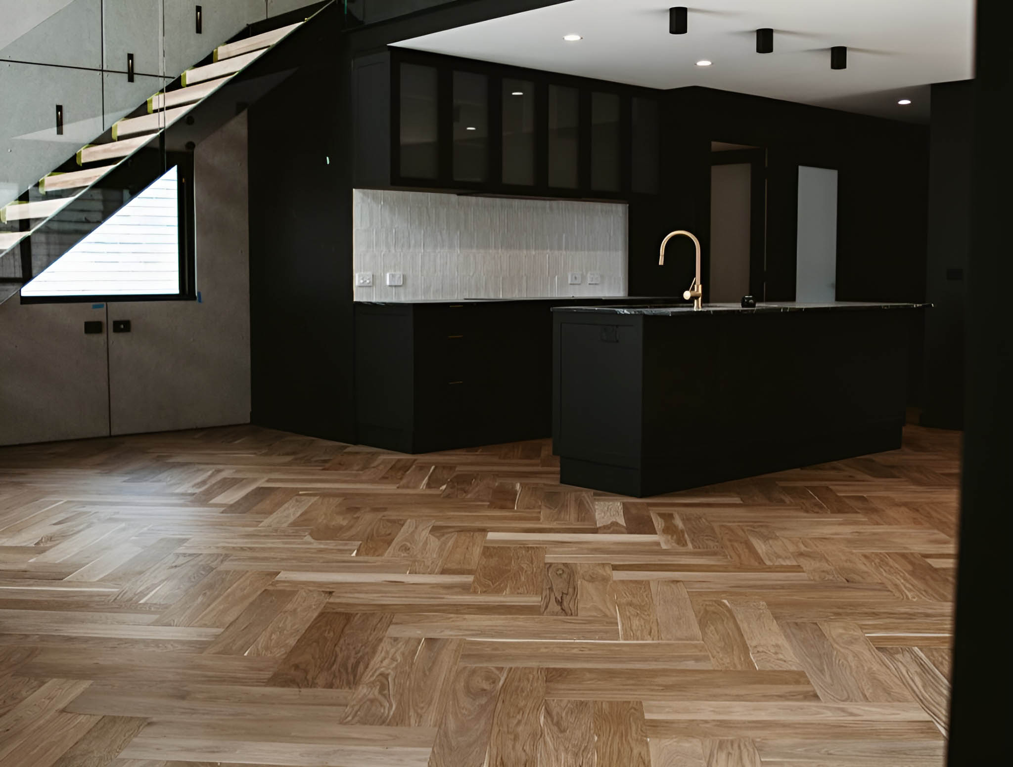 1-home-timber-wood Light timber herringbone floor in a kitchen with black cabinetry