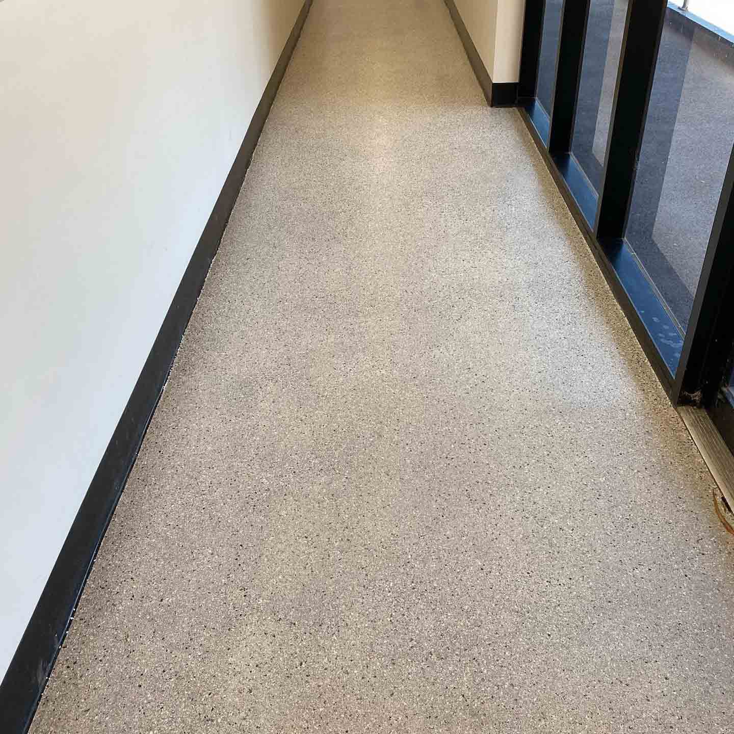 After: the same glazed corridor with an even, clean speckled floor