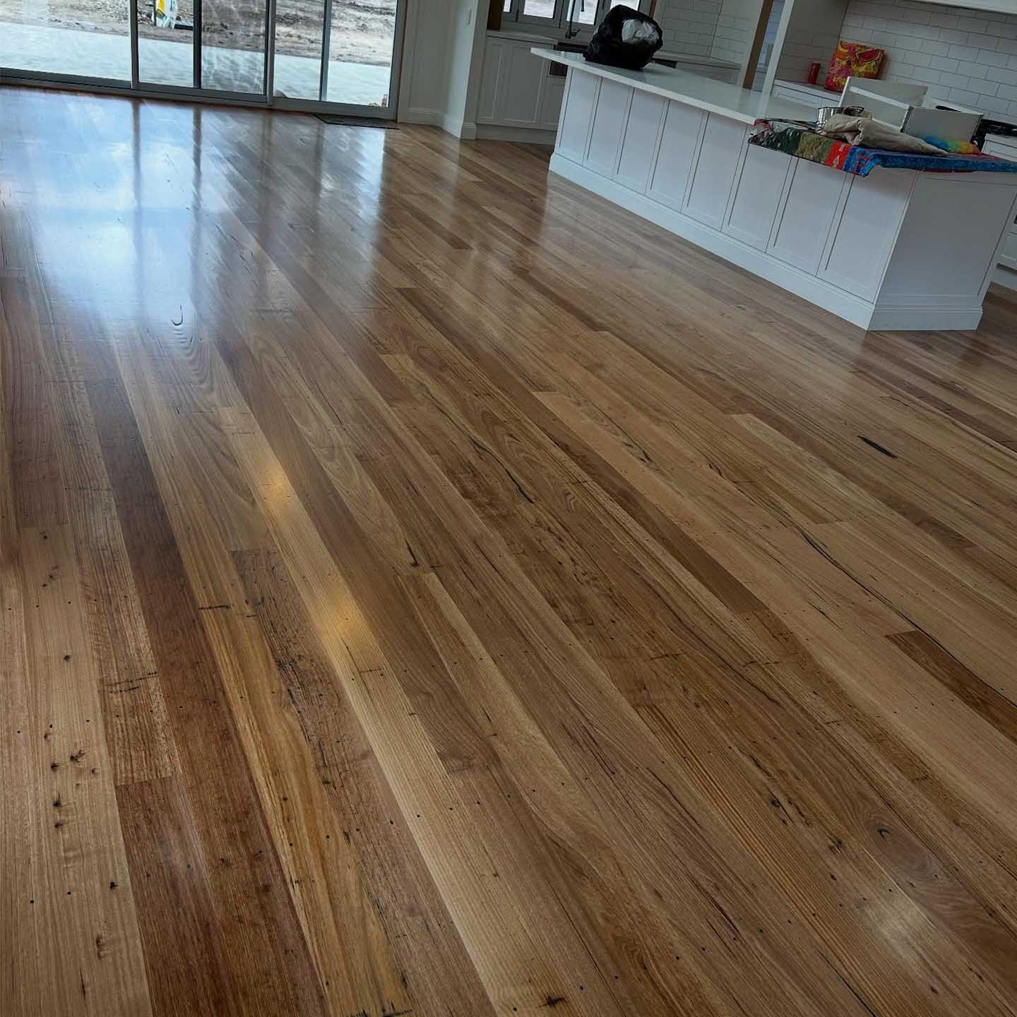 After: glossy finished timber floor in the same open-plan kitchen
