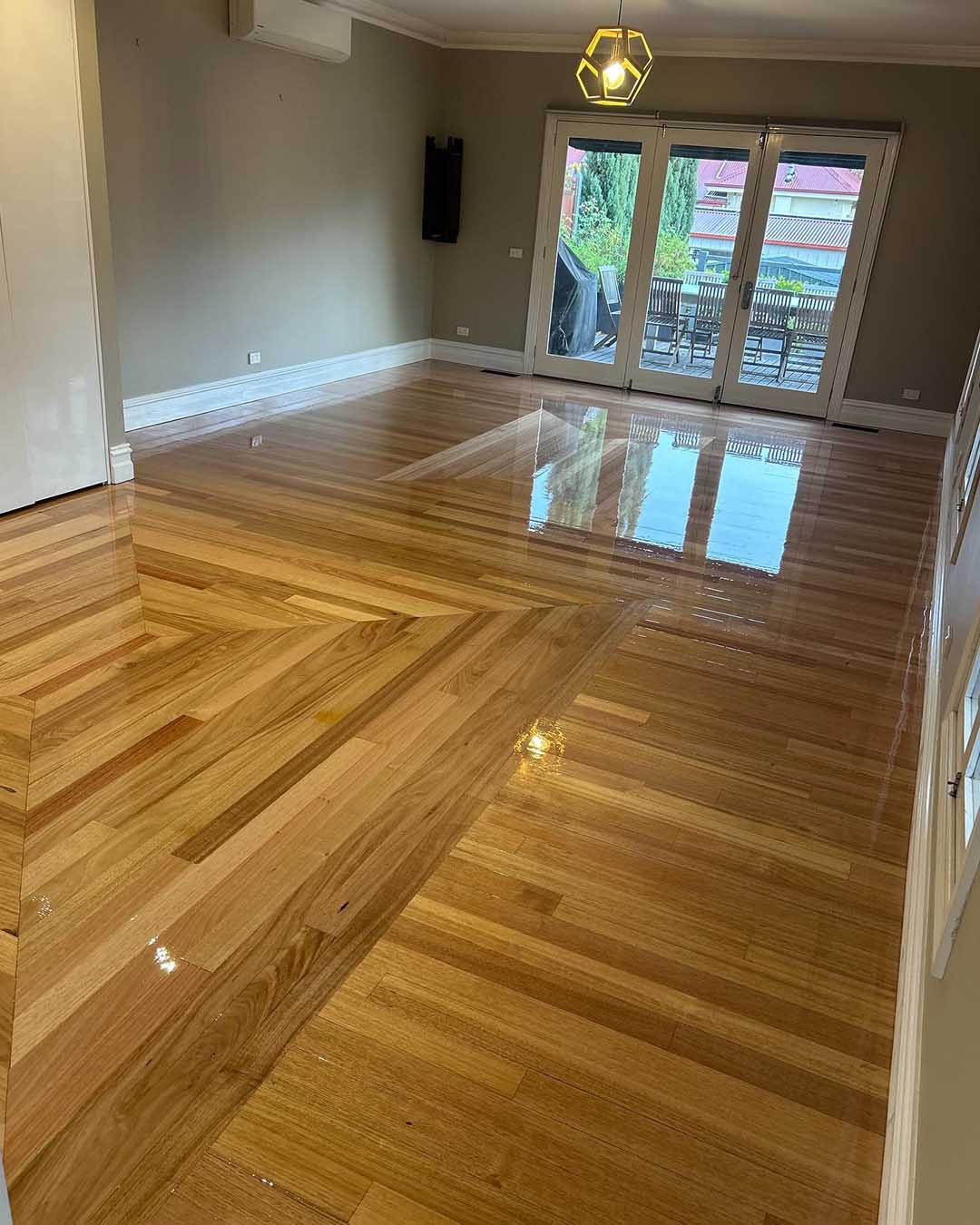 Glossy timber floor with a chevron feature in an empty living room