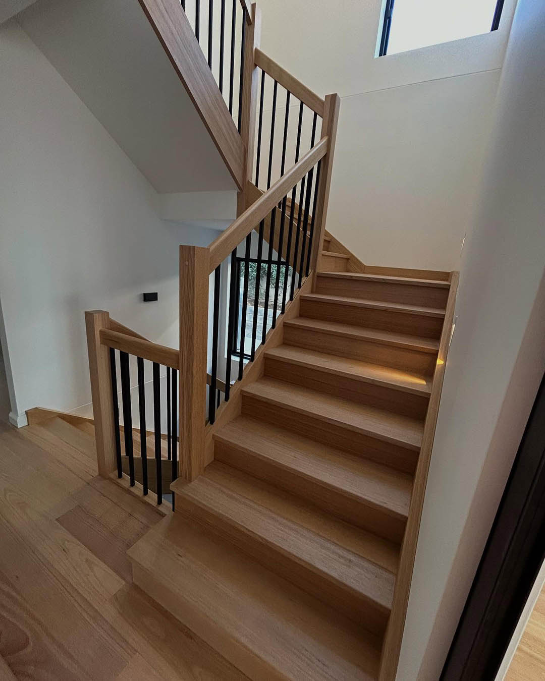 Timber staircase with black balusters and a timber handrail