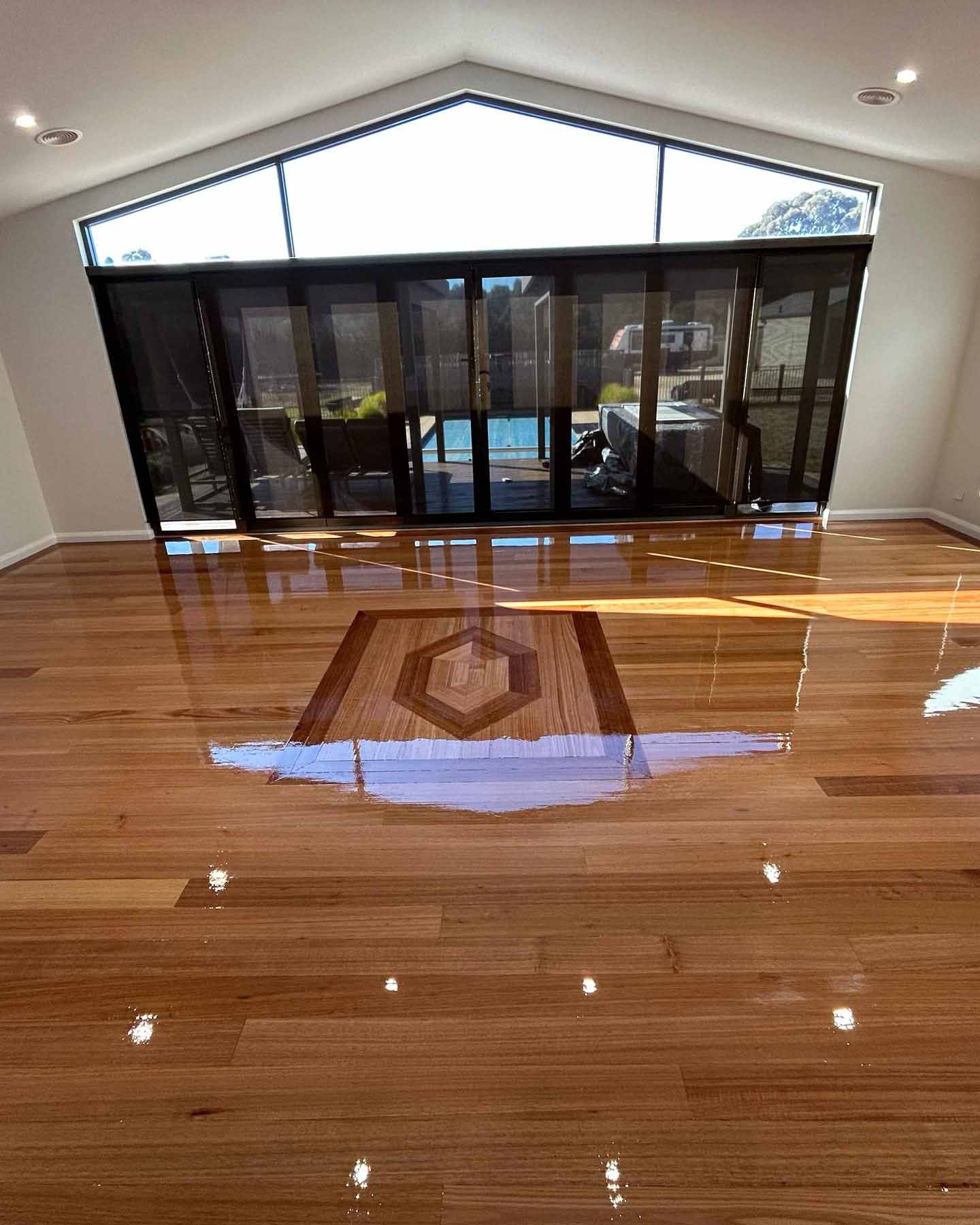 faq1 Glossy timber floor with a diamond-shaped inlay below a raked window wall