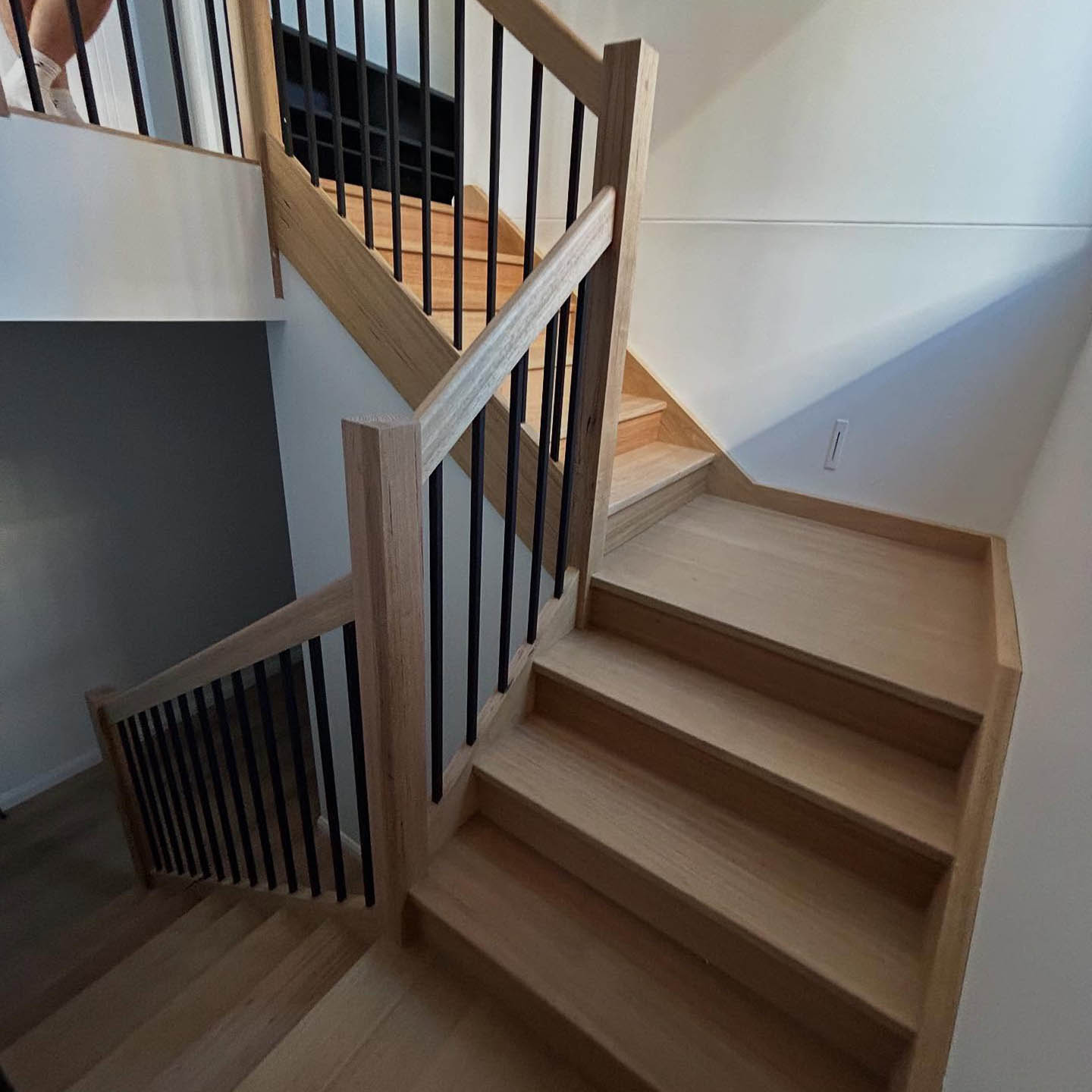 faq2 Timber staircase with black balusters turning at a landing